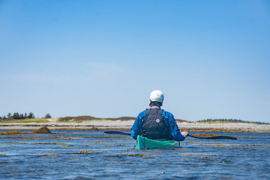 Person kayaking on a calm Atlantic ocean with clear blue sky